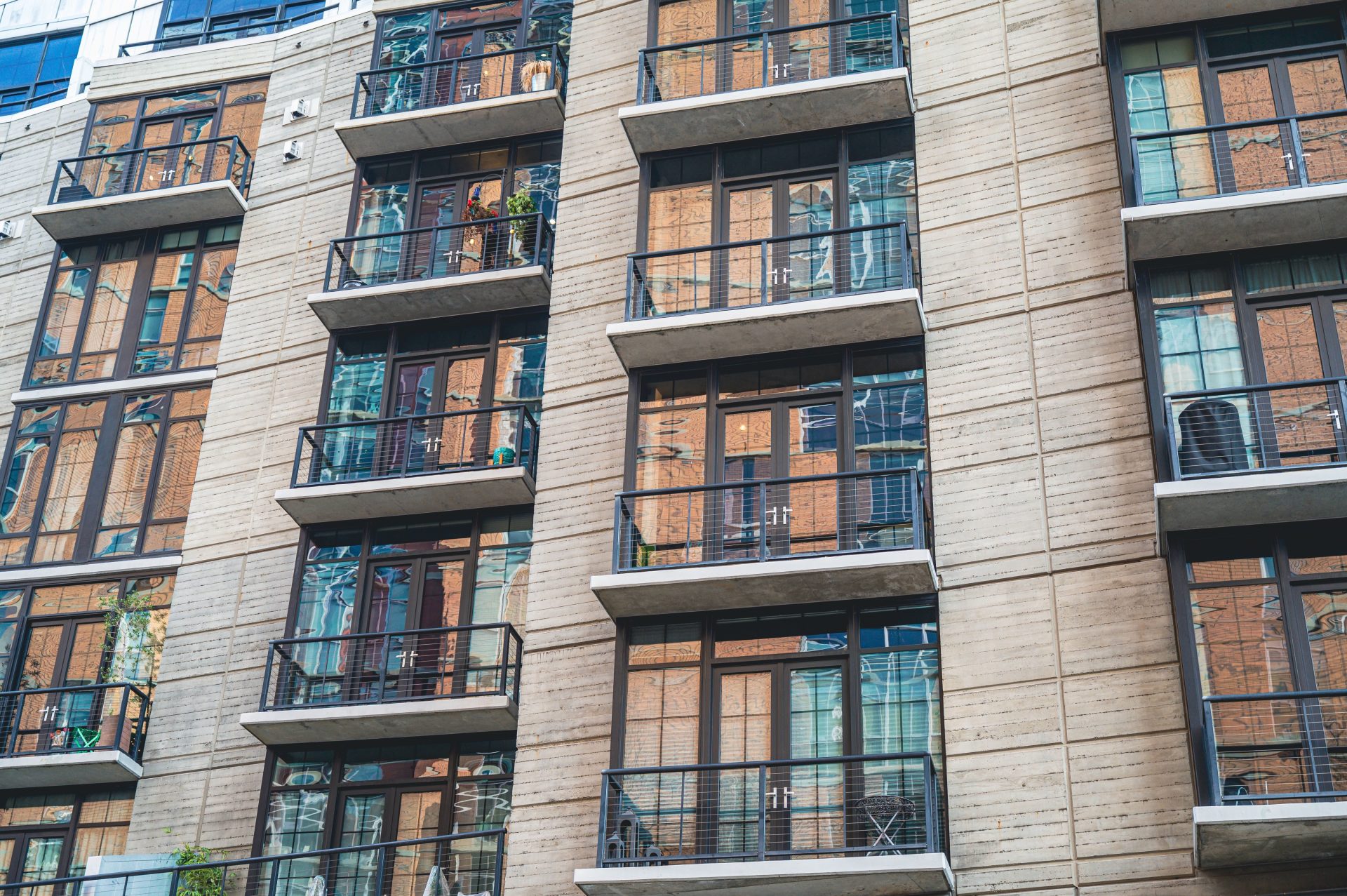 Außenansicht eines modernen Apartmenthauses mit Betonfassade und Glasbalkonen.