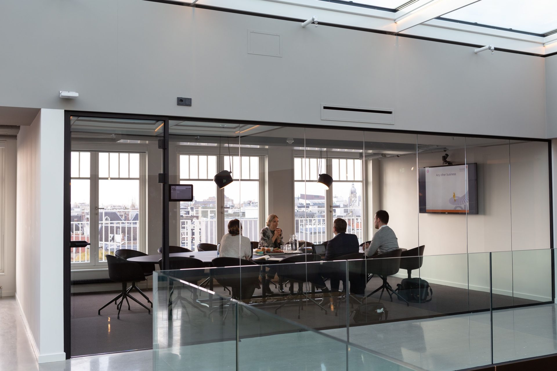 Ein geschäftliches Treffen in einem modernen Büro mit Glaswänden und Blick auf die Stadt in Amsterdam.