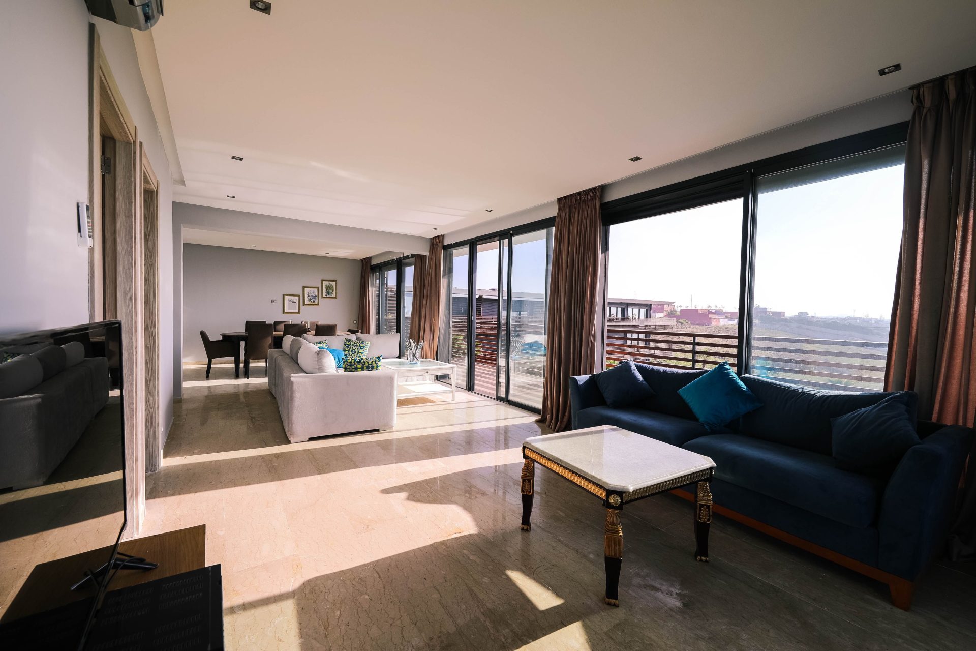 Helles und luftiges, modernes Wohnzimmer mit Einrichtung und großen Fenstern, die den Blick auf die Stadt freigeben.