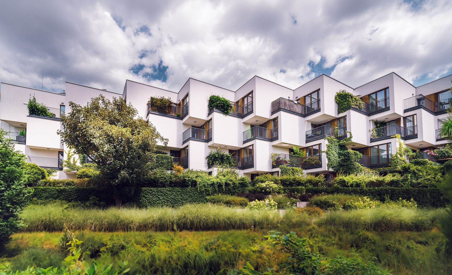 Moderner Apartmentkomplex mit nachhaltiger Architektur, üppiger Begrünung und offenen Balkonen.
