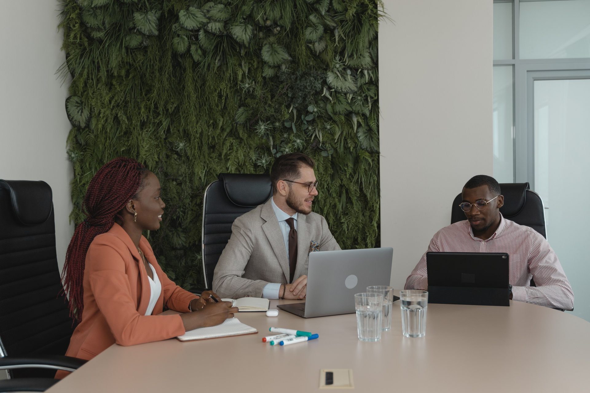 Ein vielfältiges Team arbeitet in einem modernen Büro mit vertikalem Garten zusammen.