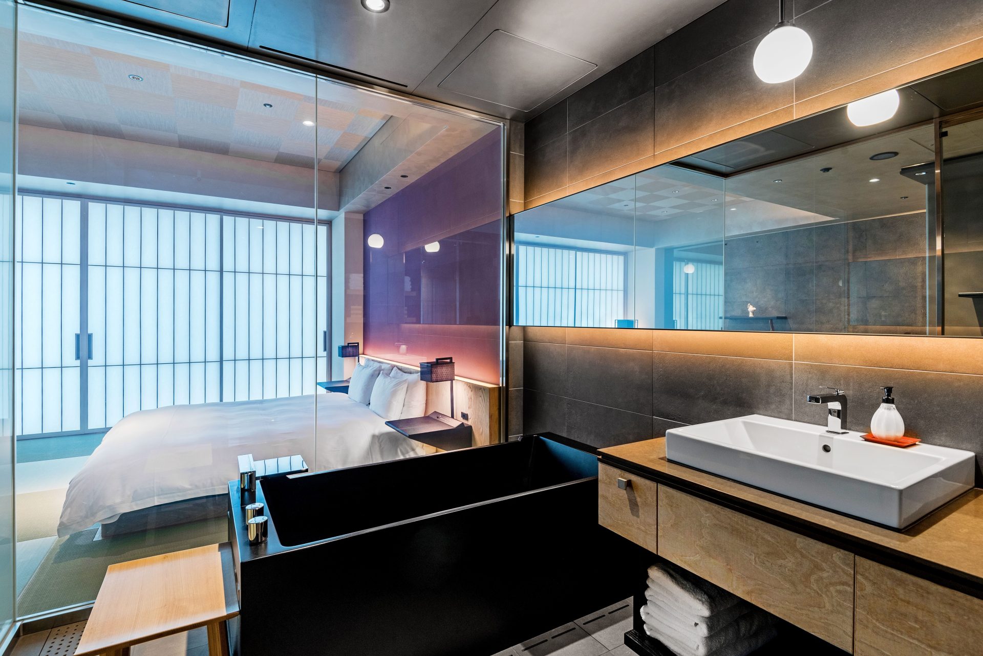 Elegantes Hotelbadezimmer mit Blick durch eine Glastür auf ein stilvolles Schlafzimmer, das luxuriöses Interieur präsentiert.